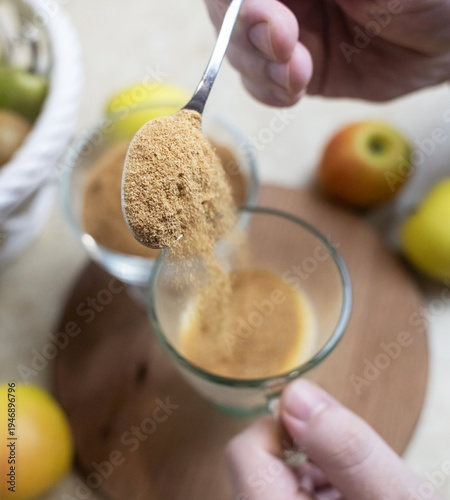 Wallpaper Mural Person adding apple fiber powder to a glass of yogurt, surrounded by fresh apples and walnuts. Healthy prebiotic supplement for gut health, digestion and weight management. Torontodigital.ca