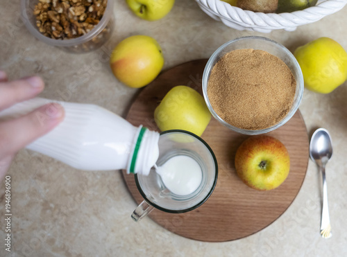 Wallpaper Mural Person adding apple fiber powder to a glass of yogurt, surrounded by fresh apples and walnuts. Healthy prebiotic supplement for gut health, digestion and weight management. Torontodigital.ca