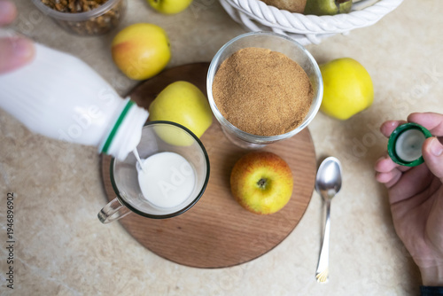 Wallpaper Mural Person adding apple fiber powder to a glass of yogurt, surrounded by fresh apples and walnuts. Healthy prebiotic supplement for gut health, digestion and weight management. Torontodigital.ca