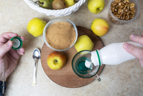 Wallpaper Mural Person adding apple fiber powder to a glass of yogurt, surrounded by fresh apples and walnuts. Healthy prebiotic supplement for gut health, digestion and weight management. Torontodigital.ca