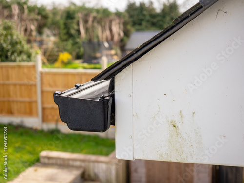 roof upvc plastic eaves gutter detail with end cap on the gable elevation showing roofing slates and sarking felt.