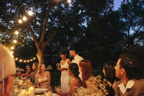 Celebration of a romantic evening wedding dinner under outdoor lights with friends