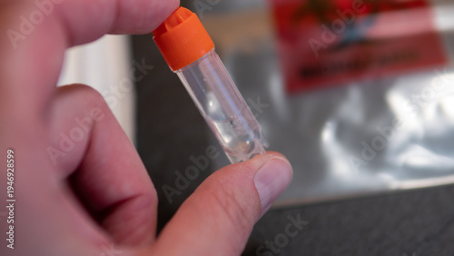 Foto Hand holding DNA saliva sample collection tube from home genetic ancestry testing kit