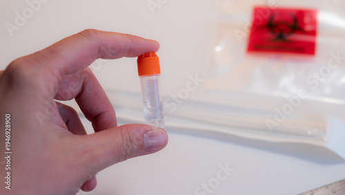 Fotografie Hand holding DNA saliva sample collection tube from home genetic ancestry testing kit
