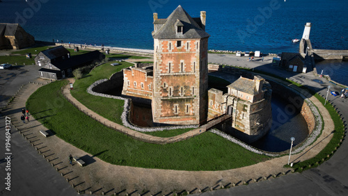 Aerial view of Vauban tower, a historic sandstone fortress embraced by a moat and verdant grass against the backdrop of the sea, Camaret-sur-Mer, Bretagne, France.