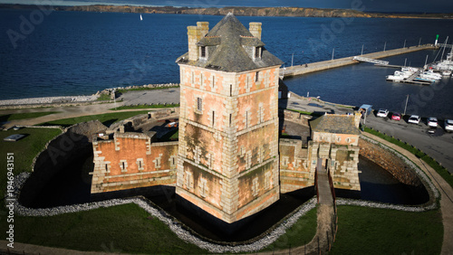 Aerial view of a fortress standing stalwart against the azure sea, its stone walls aged by time, reflecting the sun's golden kiss, Camaret-sur-Mer, Bretagne, France.