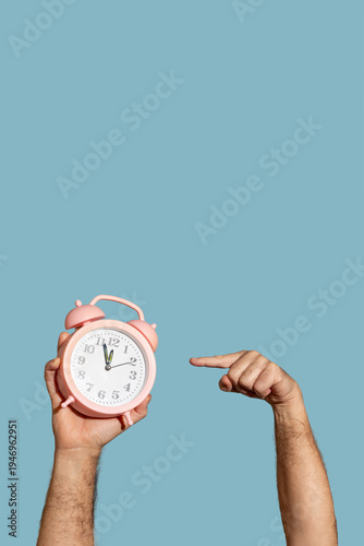 Senior man pointing finger at pink alarm clock, time management and deadline concept