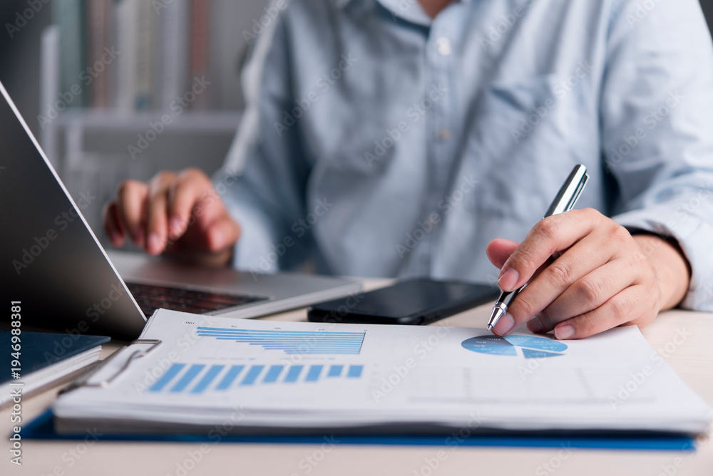Fototapeta premium businessman hands working on laptop and analyzing financial data charts, graphs, and reports at office desk. Business planning, strategy, marketing, accounting and auditing concept.
