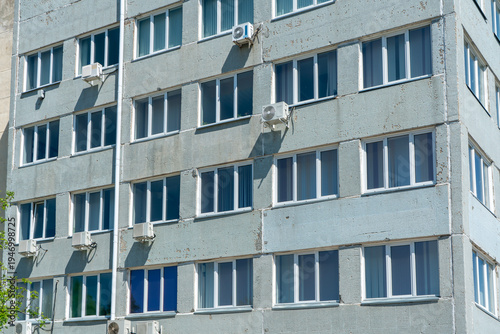 Urban Apartment Building Facade With Multiple Windows And Exterior Air Conditioners On Sunny Day