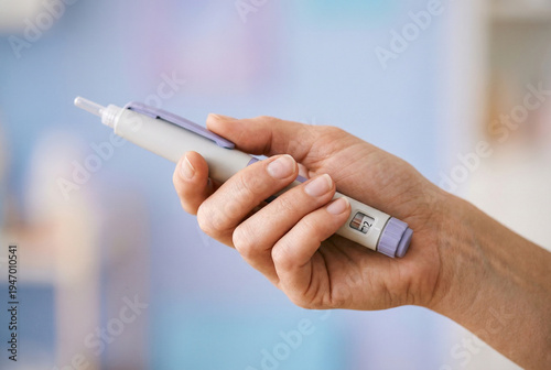 Hand holding insulin pen injector on soft blurred background, medical device for self injection and chronic disease management.