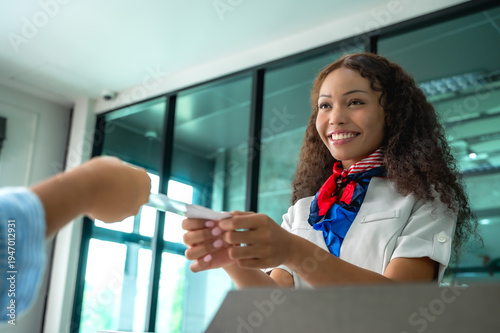 Fotografía Female ground staff in airline uniform checking passenger boarding pass at check