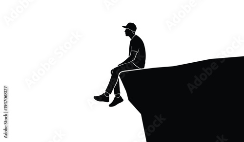 A silhouette of a young man wearing a baseball cap sitting alone on the edge of a high cliff top