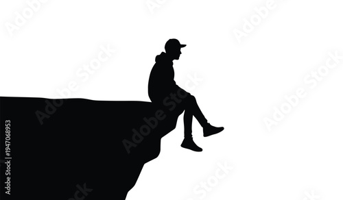A solitary young man wearing a baseball cap sitting on the edge of a high cliff looking forward