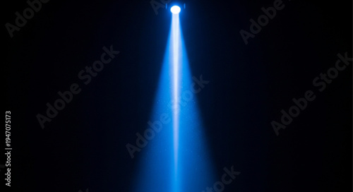 Bright blue spotlight beam shining upwards in darkness.