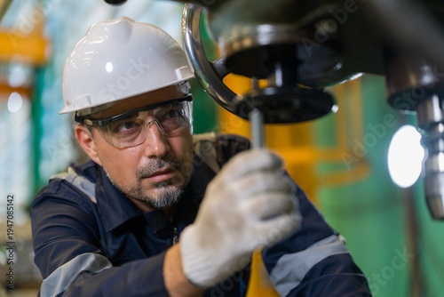 Professional technician checking industrial drill machine precision manufacturing factory. Metalworking engineer wearing safety helmet glasses operating heavy equipment mechanical maintenance workshop