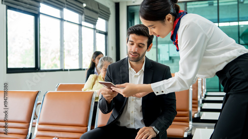 Business traveler showing passport to airline staff while sitting in airport lounge waiting area. Concept of airport passenger service air travel process, and international business travel.
