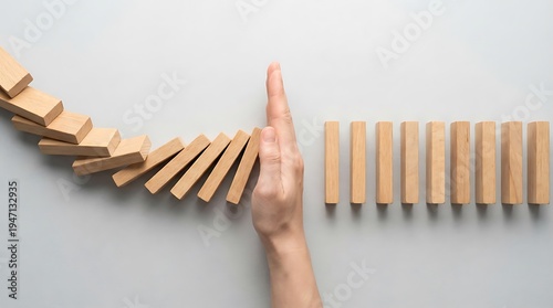 Top view of hand stopping domino effect from collapsing for risk management and business crisis control