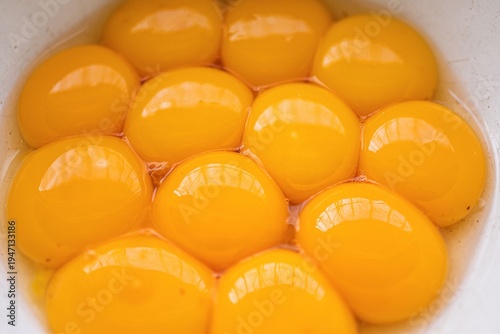 Macro close-up of egg yolks filling a white bowl