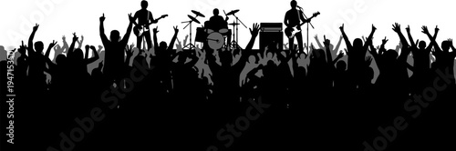 Silhouette of a band performing on stage with a cheering crowd of people raising their hands in excitement at a music concert
