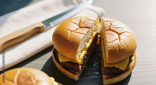 A halved cheeseburger on a cutting board with a knife