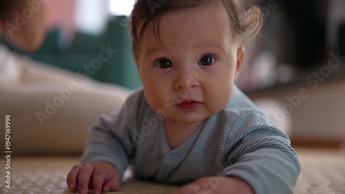 Quadro su tela Baby lying on mat indoors, lifting head with curious expression, observing surro