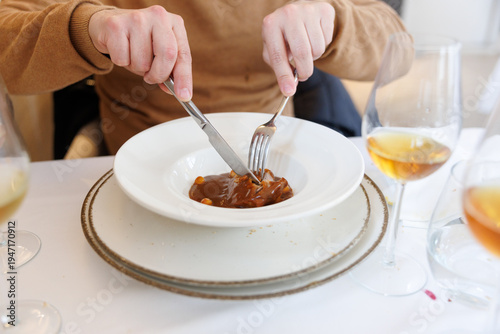 Person cutting gourmet meat dish in fine dining restaurant
