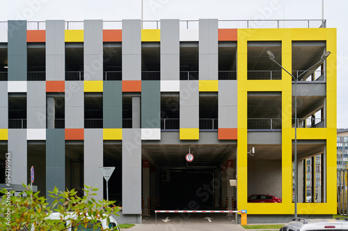 colorful modern parking garage with vivid geometric design featuring vibrant yellow, orange, and gray panels. urban architectural structure offering parking space in downtown area