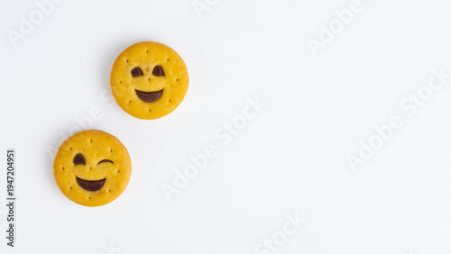 Two yellow chocolate filled emoji biscuits smiling and winking on white background with empty copy space for advertising.
