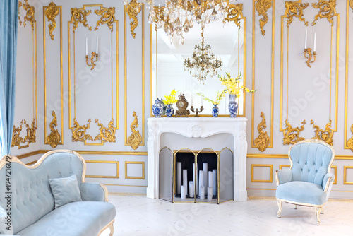 Wallpaper Mural classic interior with elegant armchairs, decorative fireplace and crystal chandelier. Bright palace style living room with blue velvet furniture, gold wall ornaments and large windows at home Torontodigital.ca