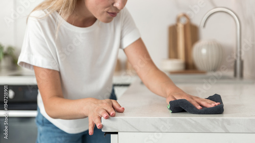 Foto Woman cleans kitchen surface in modern apartment
