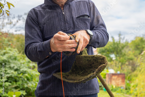 Cuadro en lienzo Man changes trimmer line for a string trimmer