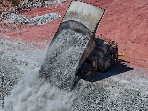 Photos Huge CAEX mining truck in the process of dumping rock material at mine waste dum