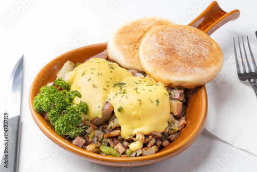 Eggs Benedict breakfast skillet with hollandaise sauce and English muffins