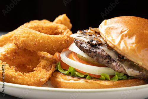 Mushroom cheese burger with onion rings on plate