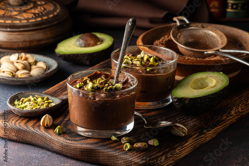 Servings of creamy chocolate avocado mousse topped with pistachio nuts.