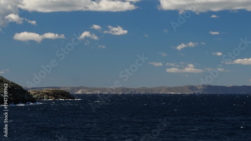Wide view of Korissia Bay on Kea Island in the Cyclades, Greece, with the lighthouse visible on the headland and wind driven waves across the Aegean Sea, filmed in late winter to early spring with nat