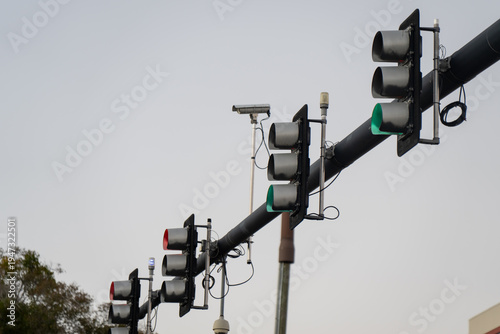 Фотография Suspended roadway traffic lights with illuminated signals, monitoring devices, a