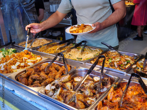 People helping themselves at an all you can eat buffet in a Chinese restaurant in Chinatown, London, UK