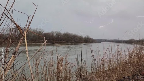 Branching lightning sequence with multiple flashes over river during daytime thunderstorm