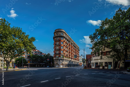 Photography Historic Wukang Mansion at a quiet Shanghai street intersection under blue summer sky, iconic European-style architecture landmark in China