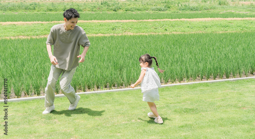Fototapeta premium A father and daughter playing tag in the lawn of their home.