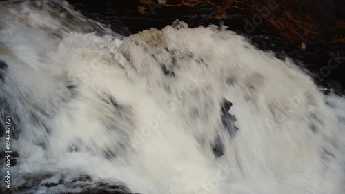 Close up of rushing river water flowing over rocks with motion blur, powerful stream in forest, natural whitewater rapids background