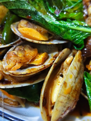 Stir-fried baby clams with chili paste and sweet basil leaf, Thai seafood dish.