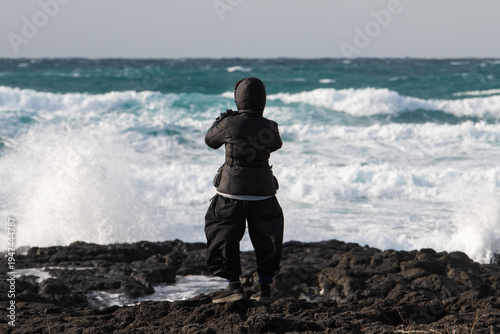 a female tourist on rocky seaside against windy sea