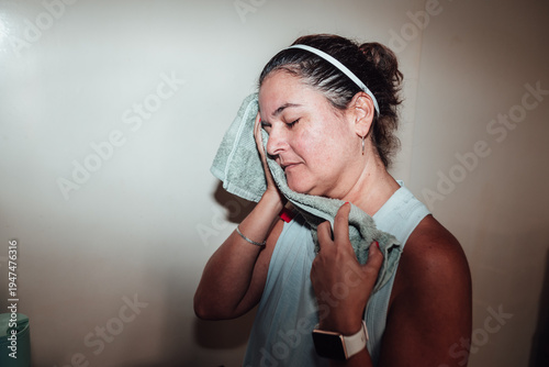 Slika na platnu Woman wipes face with towel, relaxed expression