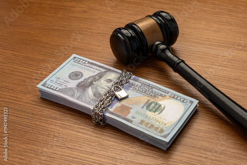 Fotografía A judge's gavel next to a stack of money bound by a metal chain and secured with a padlock