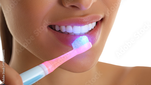 close up woman brushing teeth with electric toothbrush glowing blue light dental hygiene oral care concept isolated 