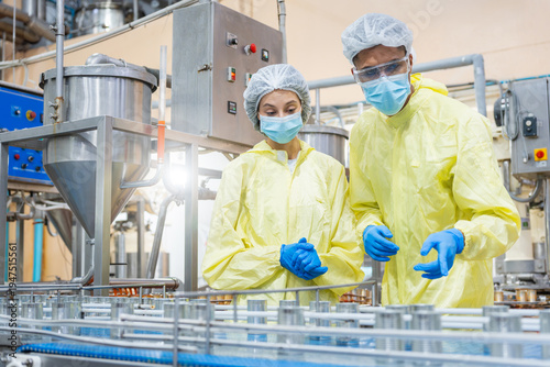 Tableau sur toile Professional inspectors in protective suits checking product quality on factory
