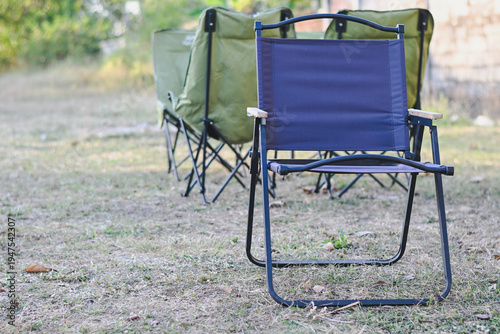 Fotografía Folding camping chairs set up on dry grass outdoors.