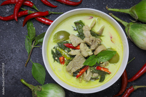 Thai food, green curry with pork in a white bowl, placed on a wooden table. Concept of authentic Thai food recipe that is very popular.